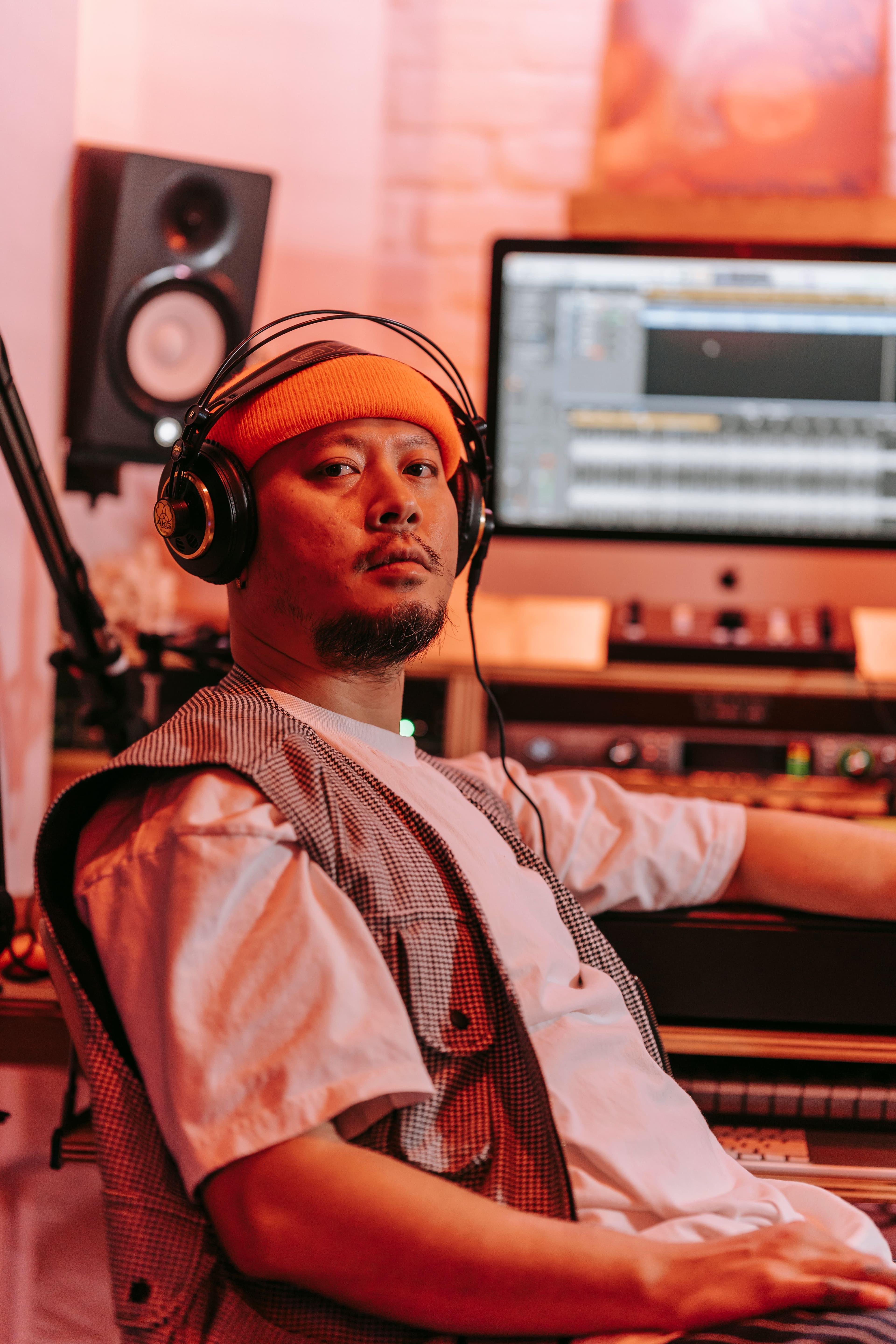 Music producer in an orange beanie at a studio workstation